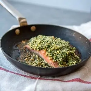 a salmon fillet in a pan with a cashew coating