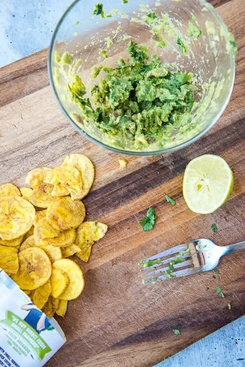 AIP guacamole in a bowl with plantain chips spread out on a cutting board