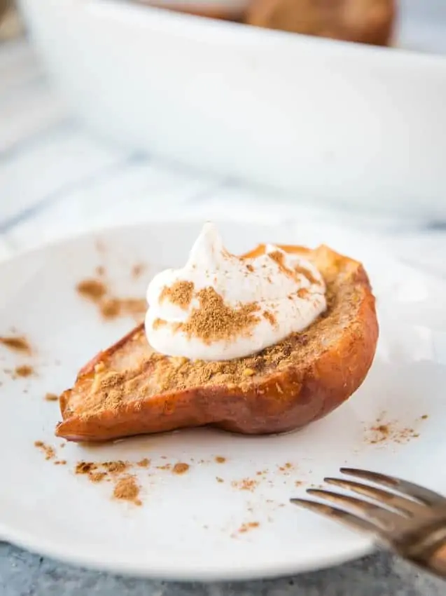 close-up of a baked pear on a plate with a dollop of coconut whipped cream on top