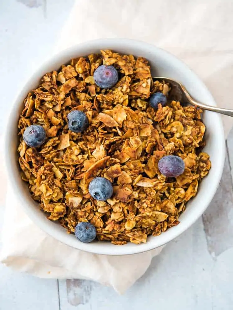 tigernut pumpkin granola from above, in a bowl with blueberries
