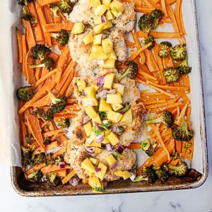 Sheet pan coconut chicken after cooking with mango salsa piled on top