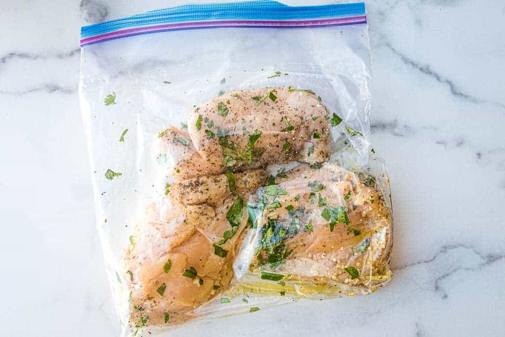 the chicken breasts marinating in a plastic ziploc bag