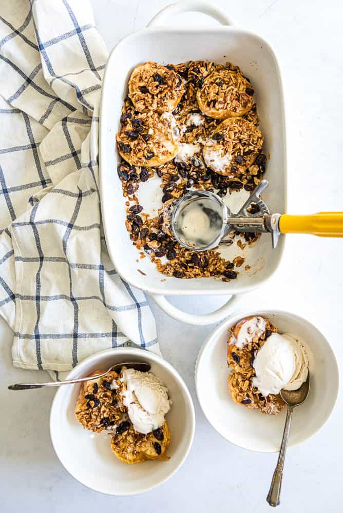 baked apples in a baking dish and 2 white bowls topped with vanilla ice cream