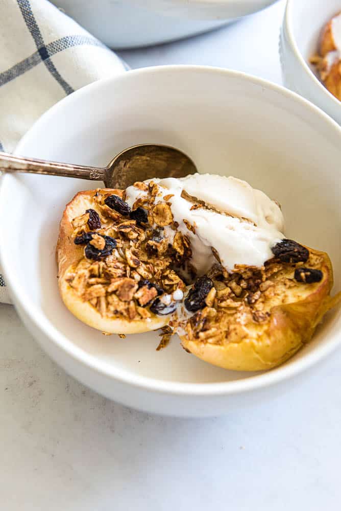 baked apples in a white bowl with vanilla ice cream