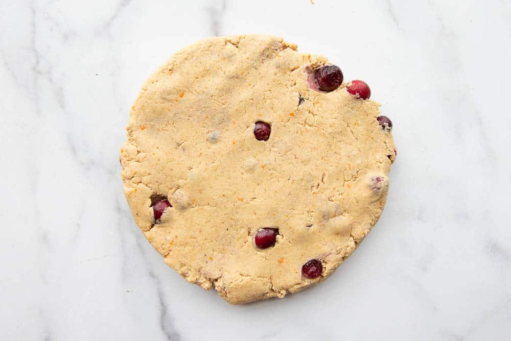 Cranberry orange scones shaped into a circle on a marble counter