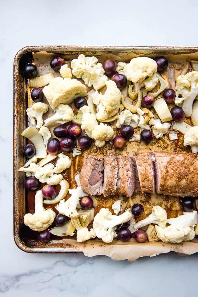 the fennel pork tenderloin laid out on a sheet pan with the cauliflower, grapes, and fennel surrounding it