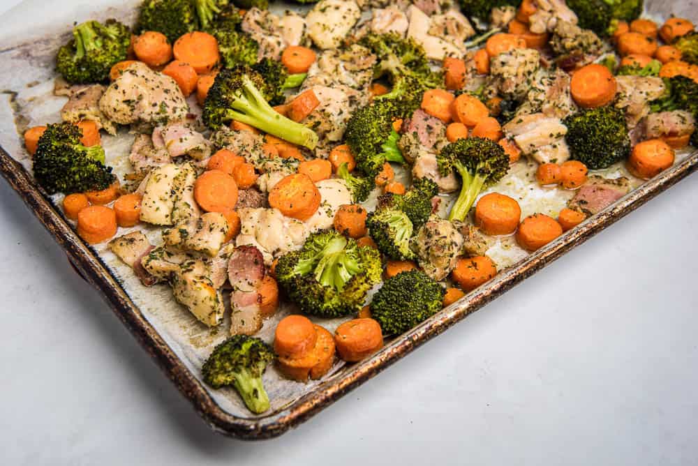 High-angle, med-shot view of sheet pan with roasted chicken, broccoli and carrots.