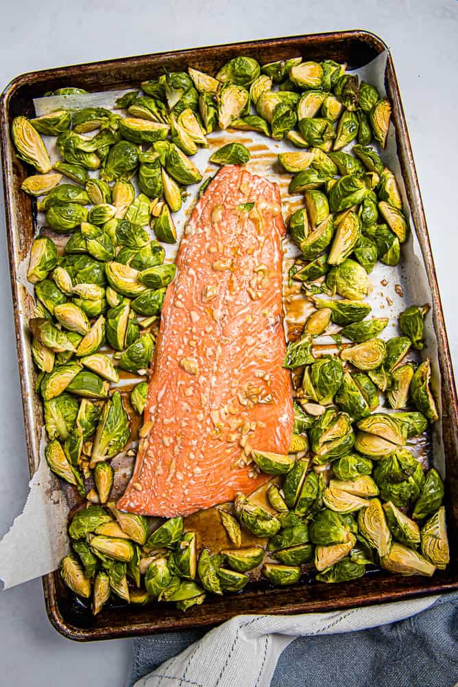 Overhead vertical view of salmon and quartered Brussles sprouts on a sheet pan
