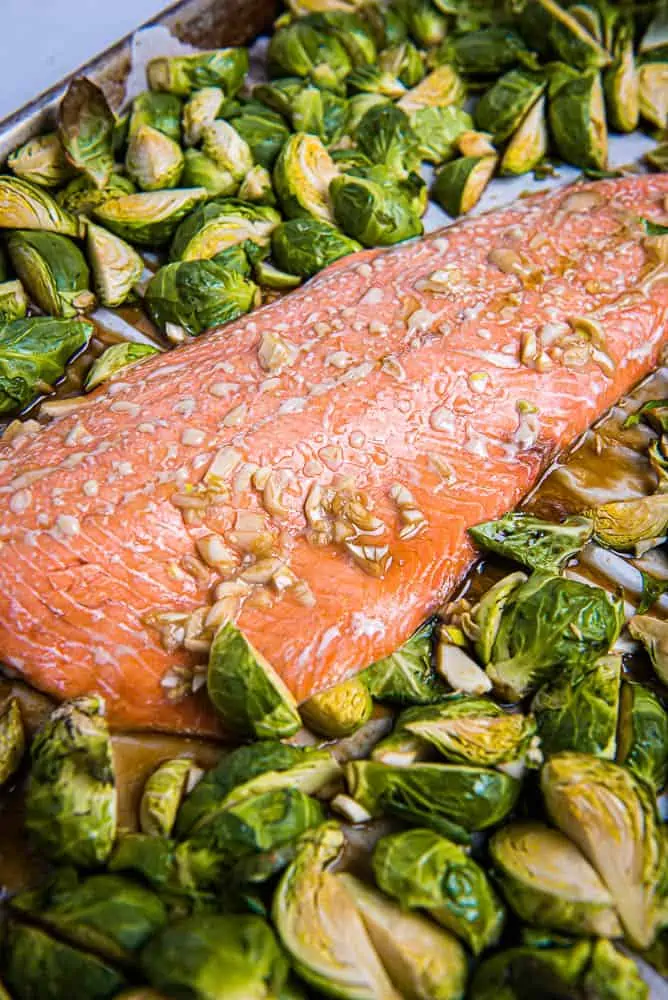 Closeup view of salmon and quartered Brussles sprouts on a sheet pan
