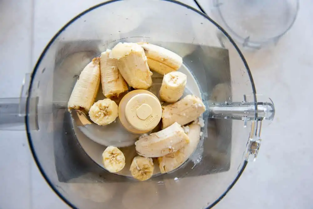 An overhead view of a blender jug with the AIP Ice Cream base ingredients, banana and milk, poured into it.