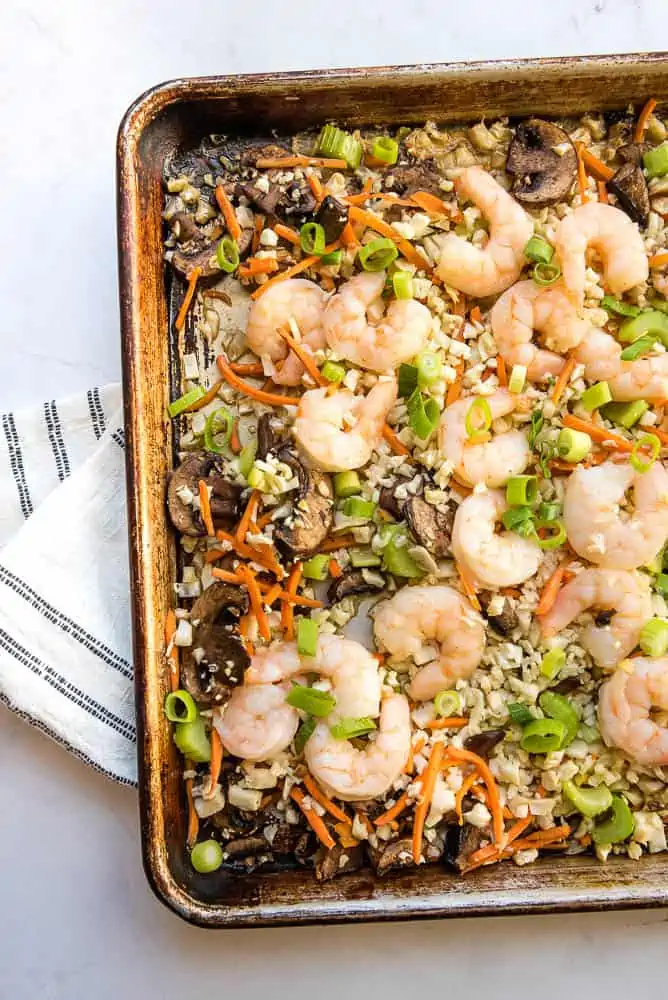 Overhead view of the left one-third of sheet pan with vegetables and shrimp